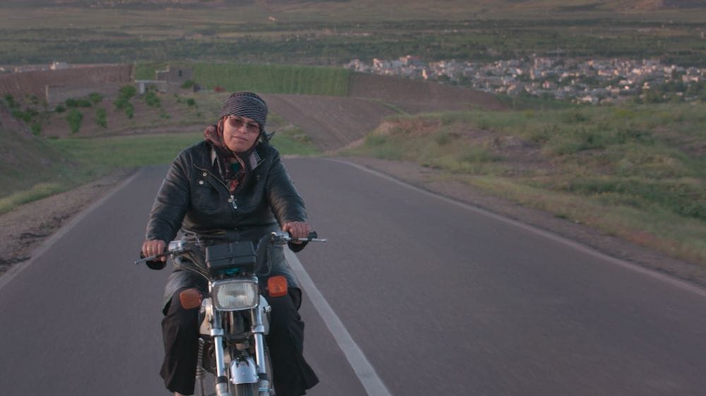 A woman clad in motorcycle leathers rides away from her village in Iran.