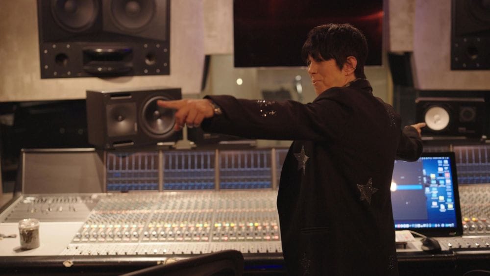 Diane Warren stands, arms outstretched, in a recording studio.