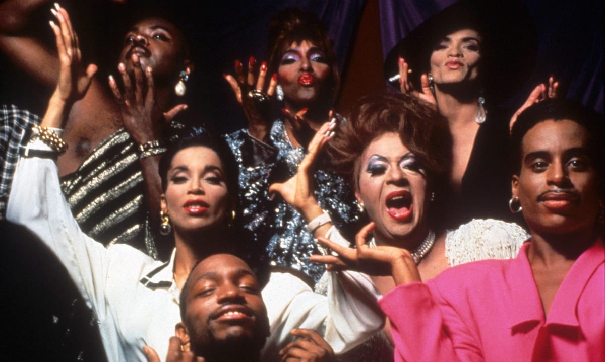 Paris is Burning: A collection of black and latin queer individuals joyfully look at the camera, posing in elaborate costumes and gesticulating with their hands.